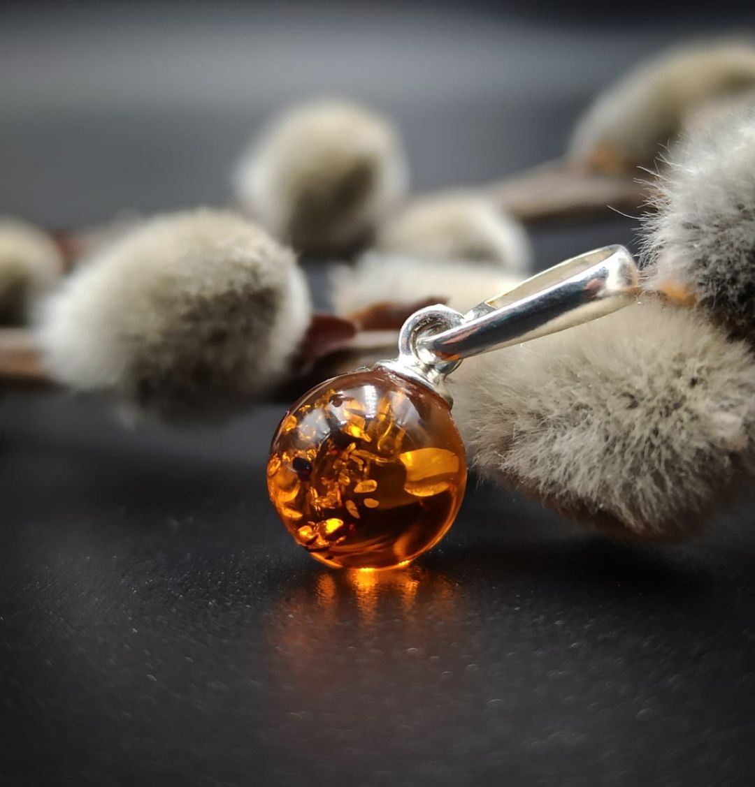 Close-up of genuine Baltic amber ball pendant in silver setting
