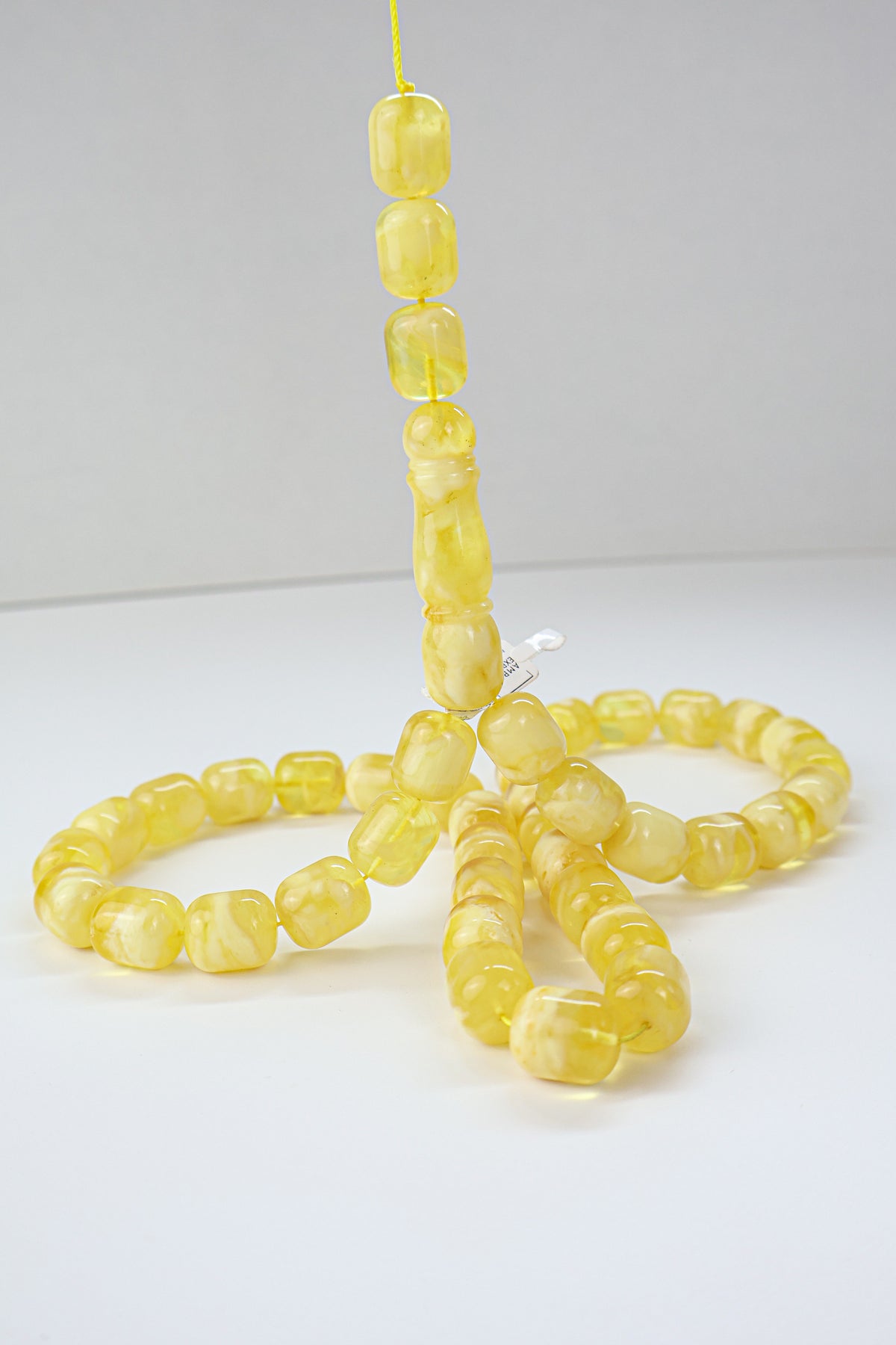 Yellow and white succinite amber tasbih featuring opaque to translucent swirled beads, weight 71.49 grams.