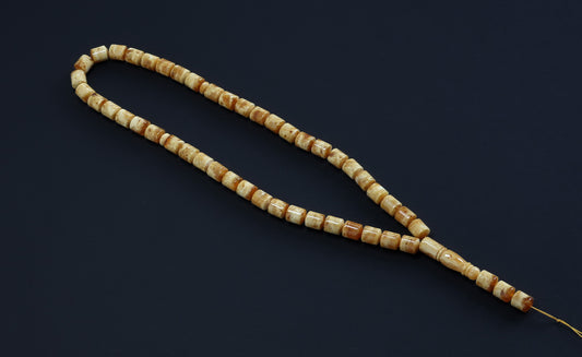 Full view of the 48-bead Islamic prayer beads (Gebetskette) by Tetibel, showing the cylindrical amber body and the traditional long, thin drop (Imam).
