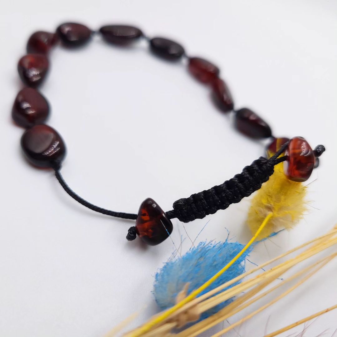 Primäransicht des Tetibel Armbands, hergestellt aus echtem Baltischem Kirschbernstein auf schwarzem Makramee-Band.
