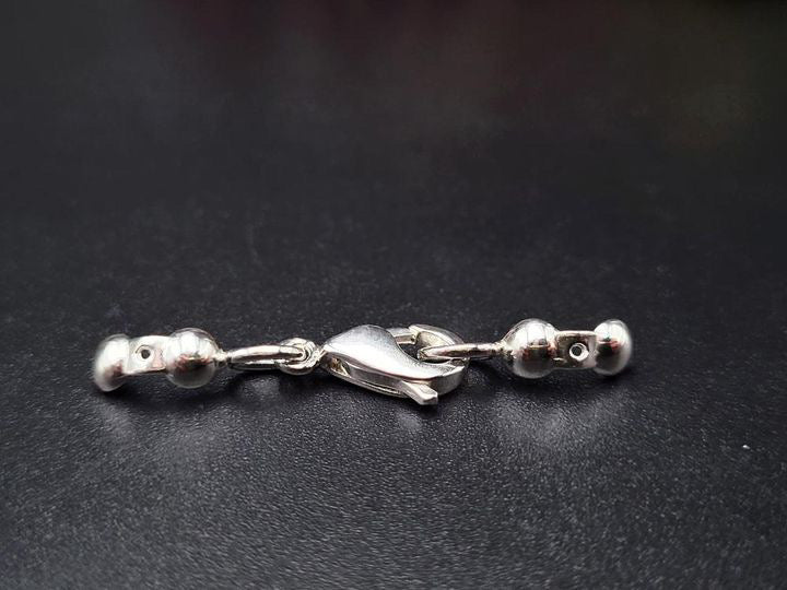 Nahaufnahme eines glänzenden Karabinerverschlusses aus 925er Sterling Silber für Halsketten oder Armbänder.