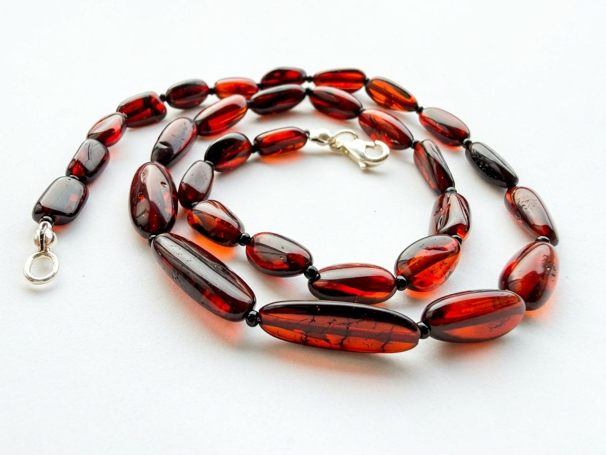Natural cherry red Baltic amber necklace display showing smooth oval beads and silver findings by Tetibel Amber Jewels.