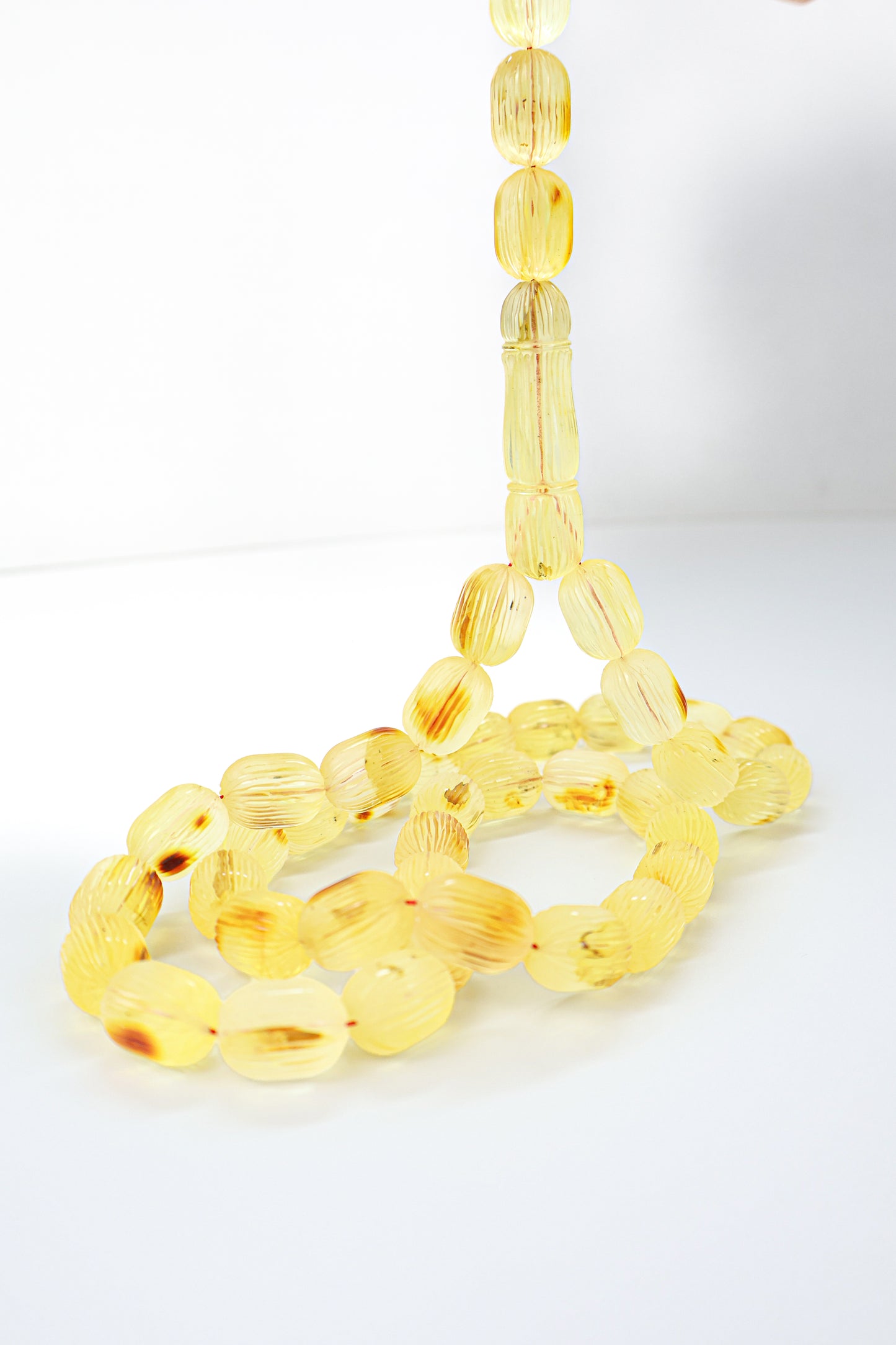 Handcrafted yellow and brown succinite amber tasbih featuring 42 authentic 16x12mm handmade carved beads with natural inclusions, weight 63.90 grams.