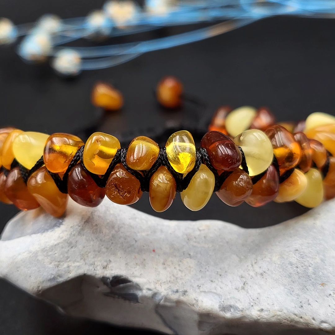 Nahaufnahme des verstellbaren Makramee-Verschlusses am Tetibel Bernstein Armband, mit zwei kleinen Bernstein-Rohsteinen als Endstücke.

