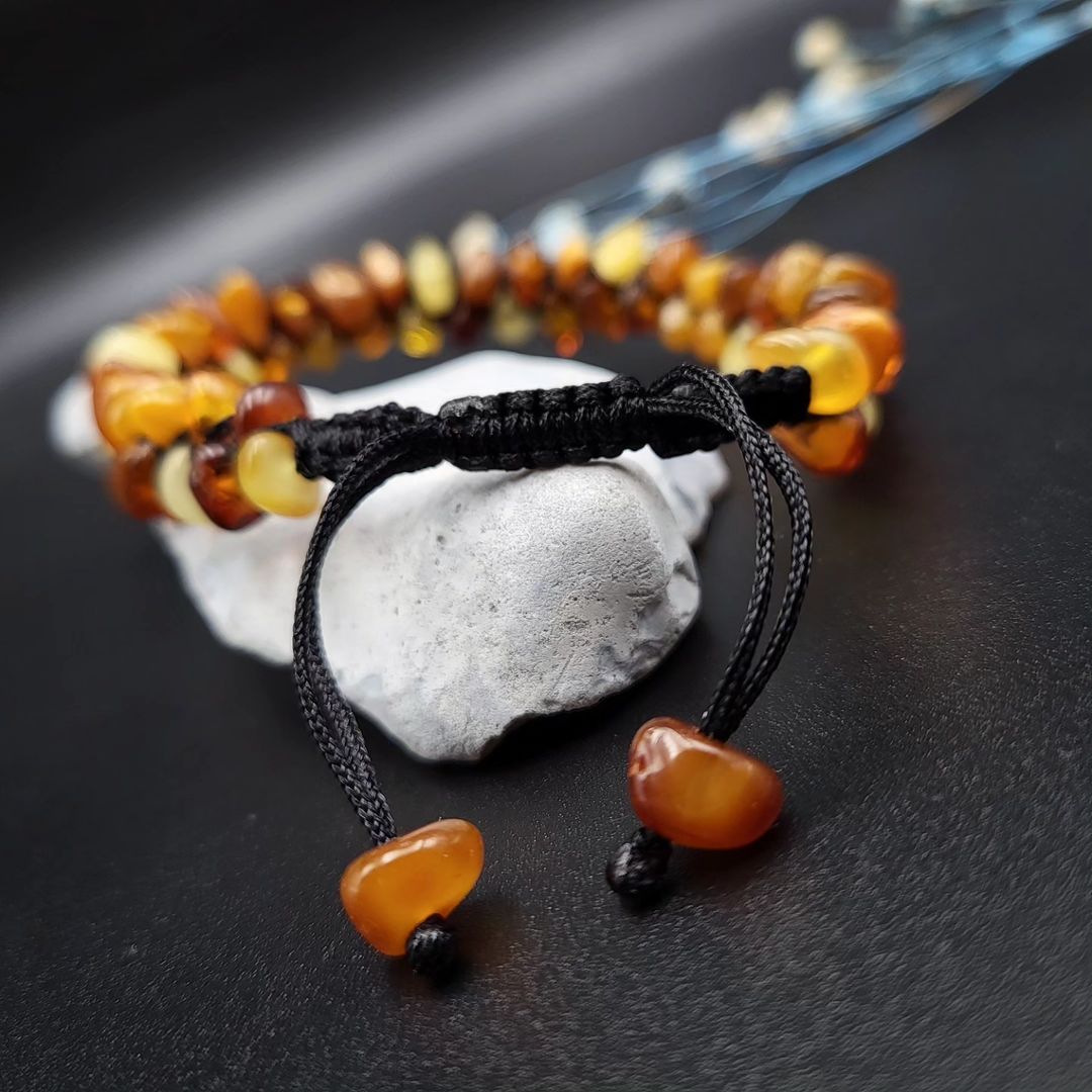 Close-up of the adjustable macramé knot closure on the Tetibel Amber Bracelet, featuring two small raw amber stones as decorative ends.