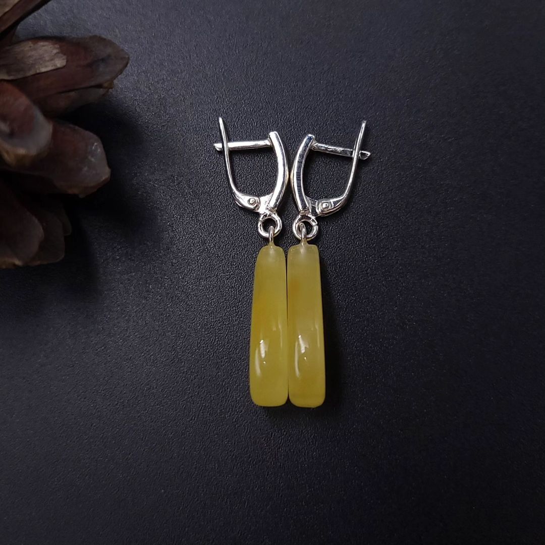 Rückansicht von ovalen Milchbernstein-Ohrsteckern in 925 Sterling Silber mit dekorativer Kordelfassung und Klappverschluss. 