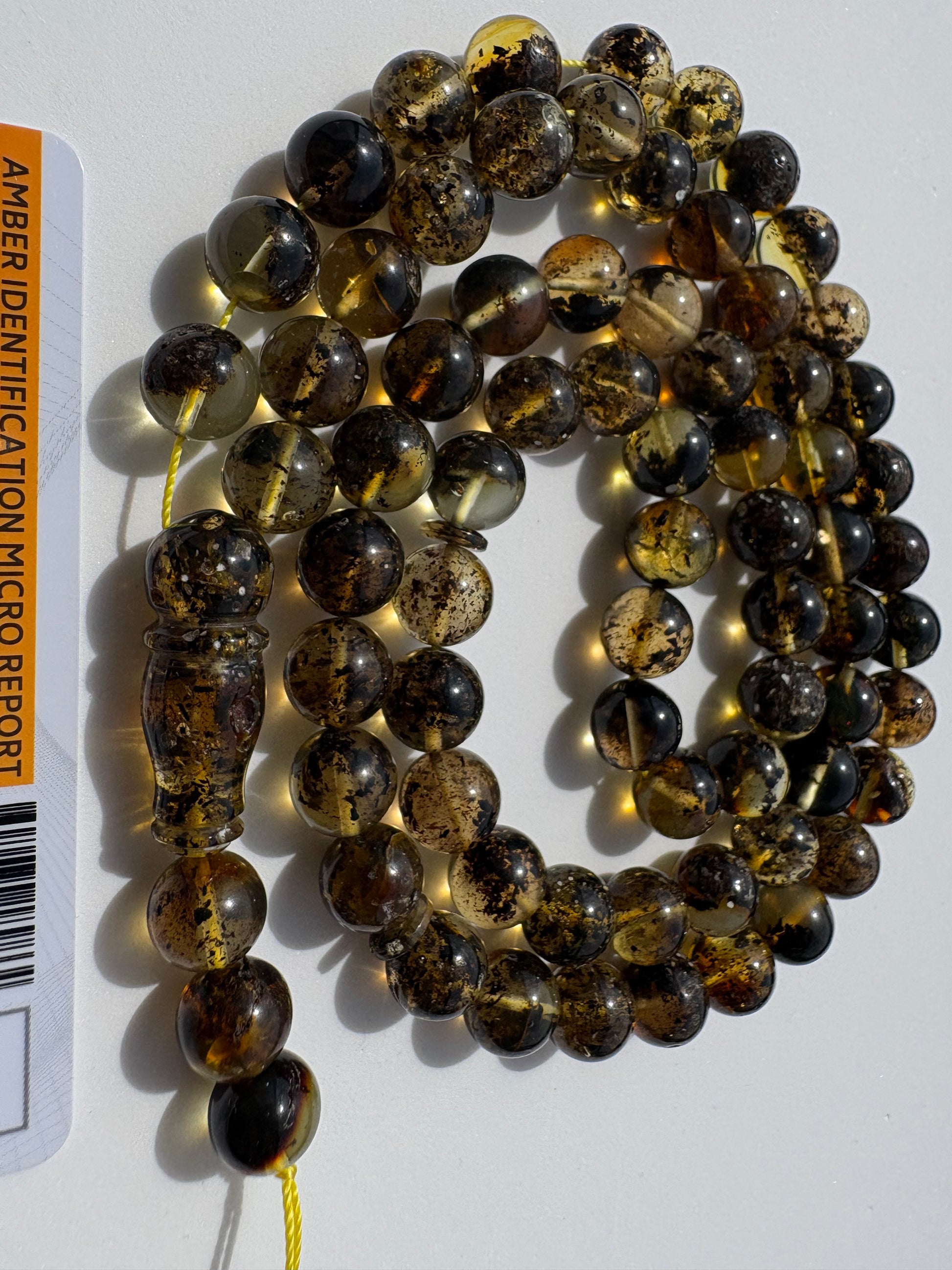 Genuine succinite amber prayer beads with natural dark inclusion patterns.
