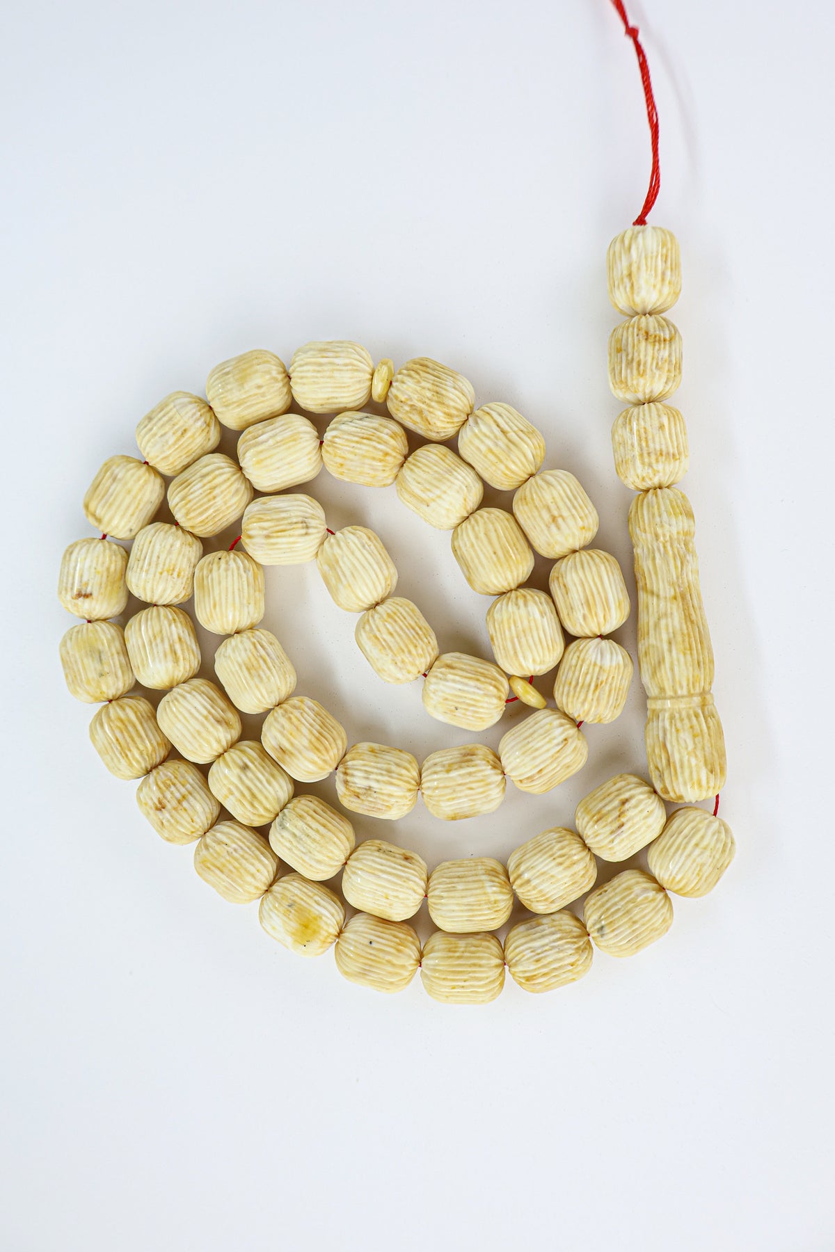 Authentic grooved hand-carved beige-brown Baltic amber misbaha strand displaying natural minor character marks and a matching carved amber imam.