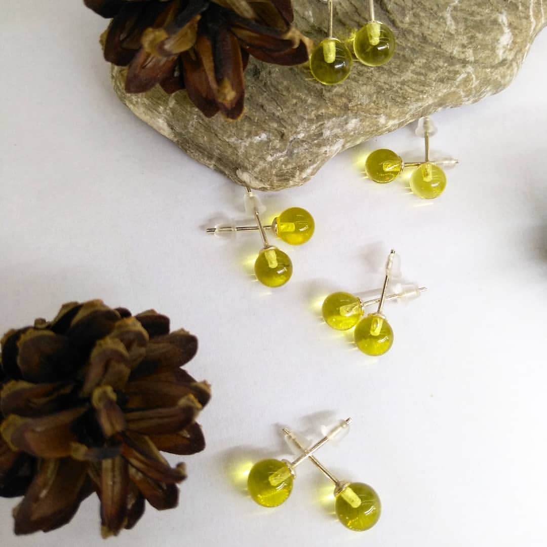 Klarer Baltischer Bernstein Ohrstecker mit 925 Sterling Silber Stiften. Ansicht betont die polierte, grüne Bernsteinkugel.