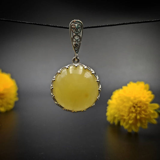 Rundes Bernstein-Plättchen in Milchgelb im Silberanhänger mit Krappenfassung.