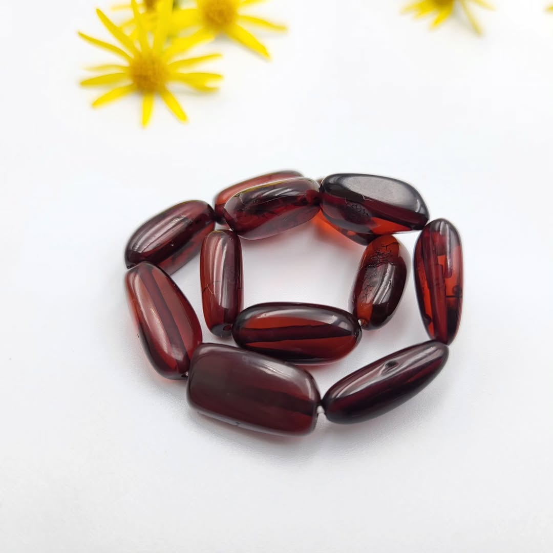 Dunkel Kirsch Bernstein Armband, präsentiert mit natürlicher Dekoration 
auf weißem Hintergrund.