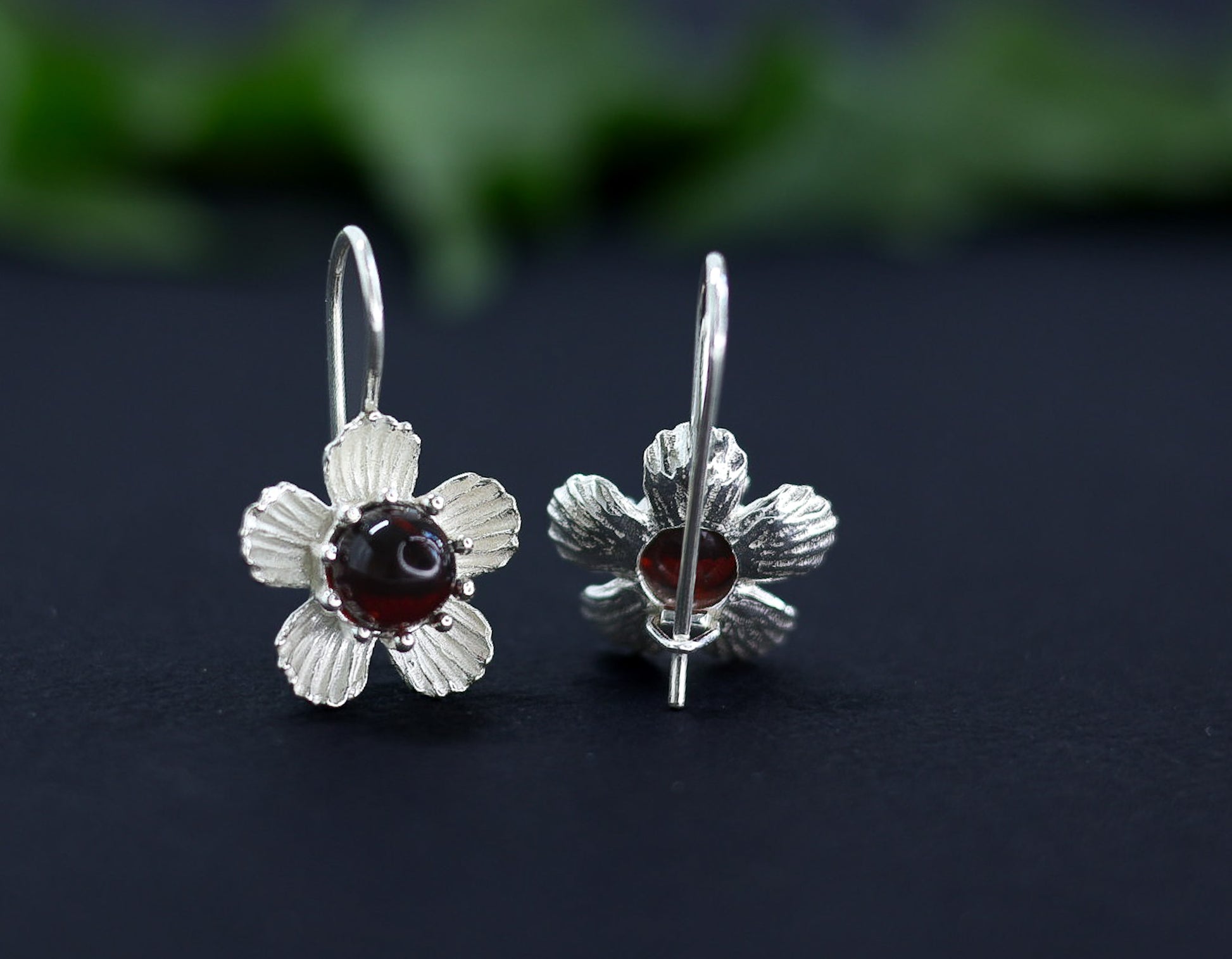 Handgefertigte Bernstein Ohrringe im Blumen-Design. Die Abbildung zeigt die strukturierte Silberfassung des Kirschbernsteins.