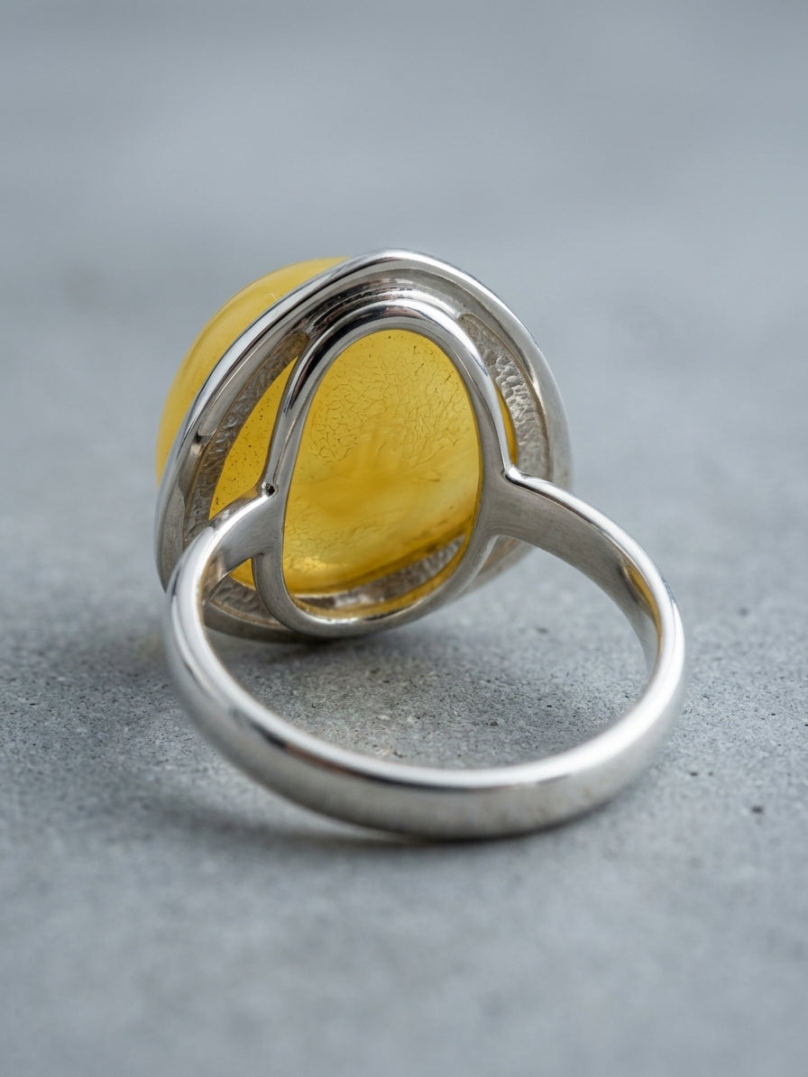 Natural butterscotch lemon yellow Baltic amber stone set in a modern open-frame sterling silver bezel ring.