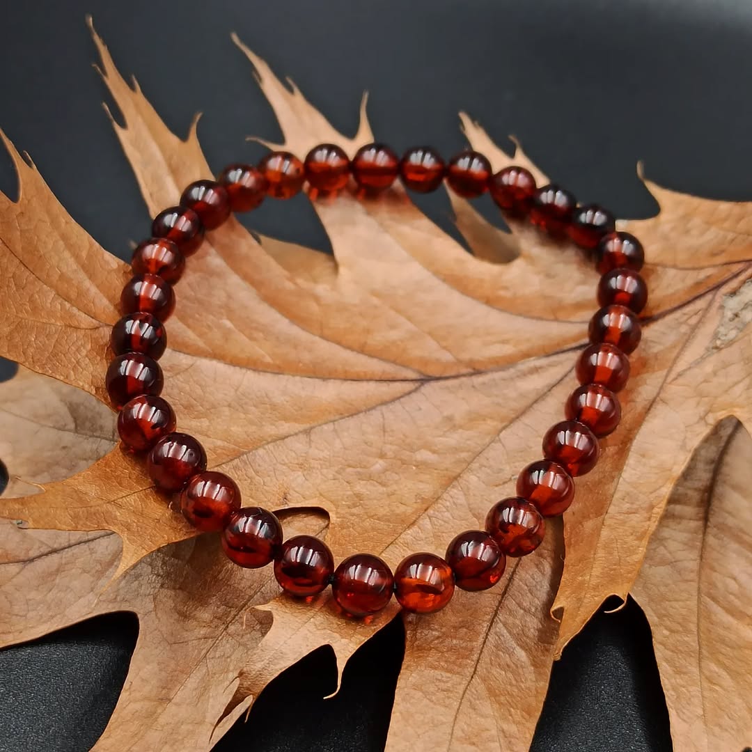 Beaded red amber bracelet on a brown leaf with a dark background