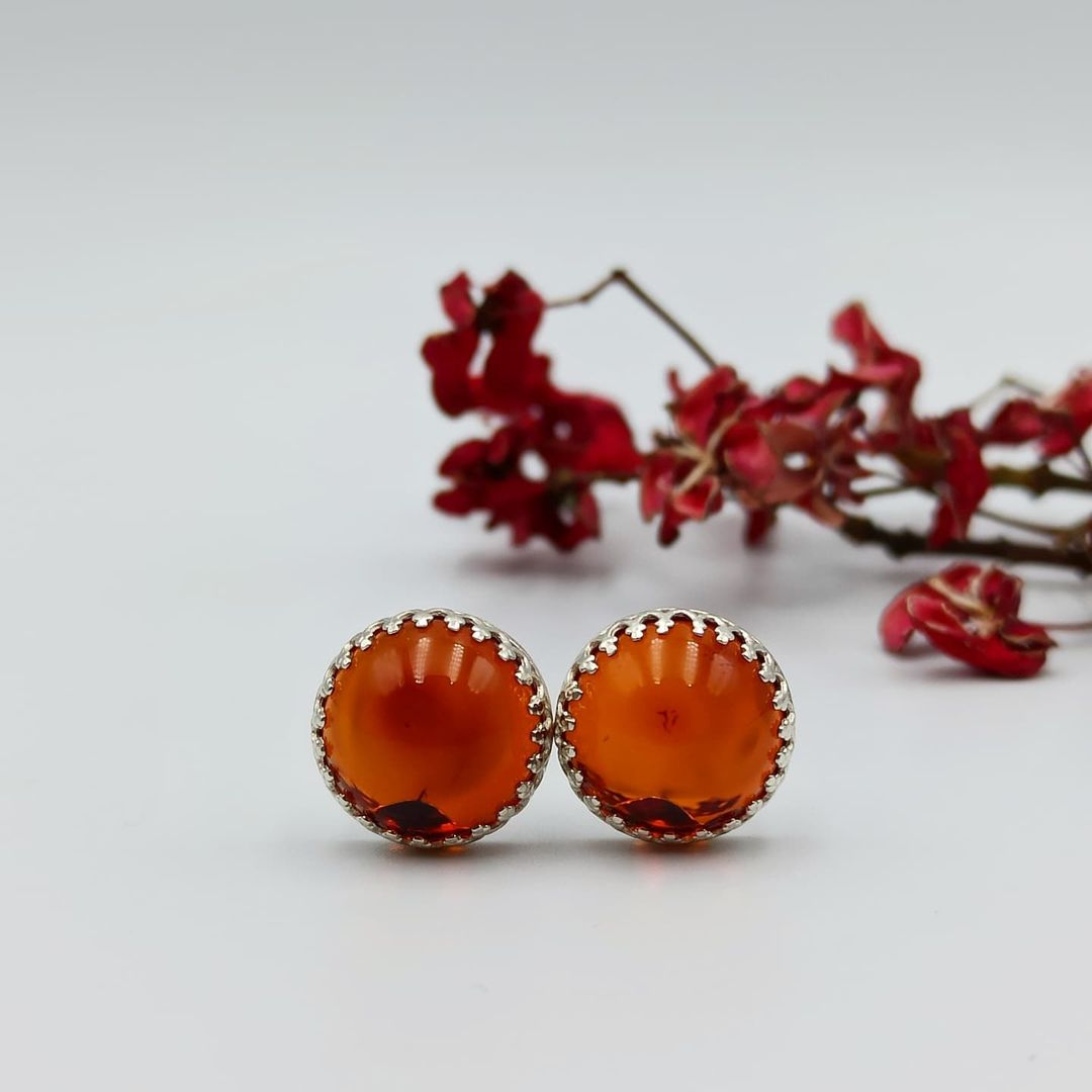 Große 12mm Cognac Bernstein Ohrstecker im Detail. Die Abbildung betont die feine Ziselierung der 925er Silberfassung.