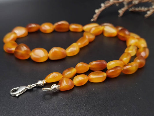 Necklace with orange beads and silver clasp on a dark background