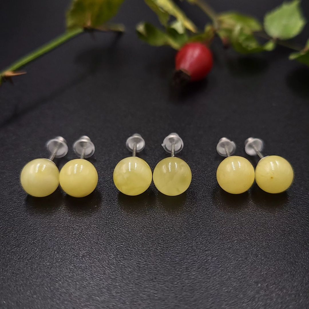 Milch-gelbe Bernstein Ohrstecker mit 925 Sterling Silber Stiften. Ansicht betont die polierten, runden Lemon Bernstein Kugeln.

