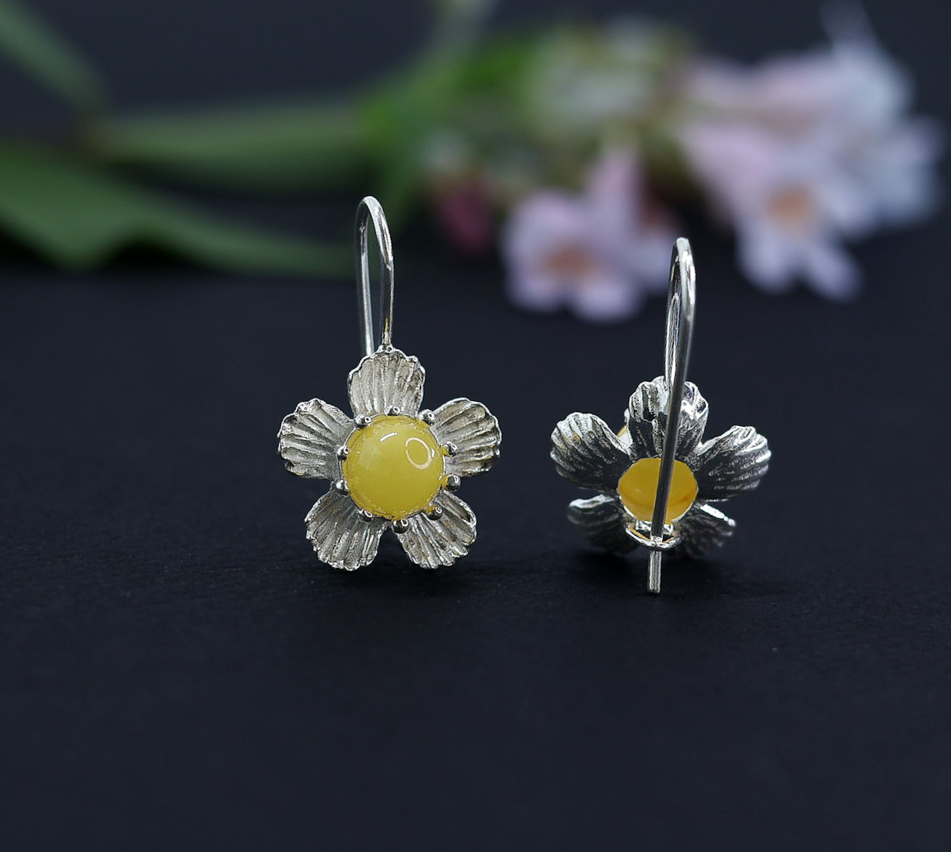 Milchgelbe Bernstein Ohrringe im Blumen-Design. Nahaufnahme der ⌀16mm Silberblüte und des zentralen Bernsteinkabochons.
