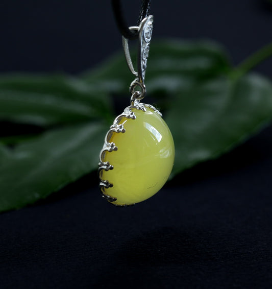 Runder Milch Bernstein Anhänger mit eleganter 925 Silber Fassung und Ornament.