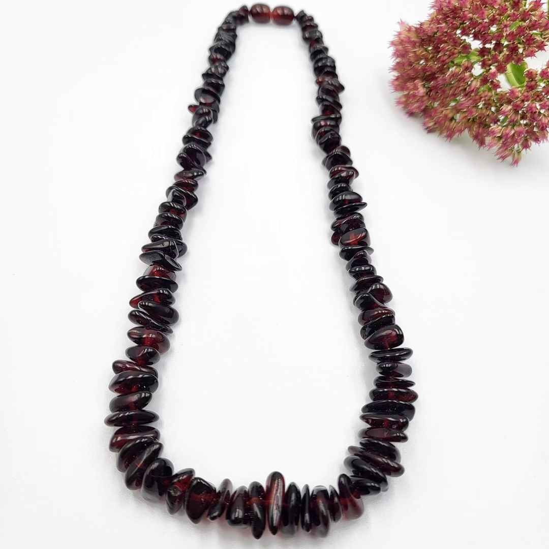 Echte Tetibel Bernstein Splitterkette in tiefem Kirschrot. Polierte Naturbernstein Nuggets auf weißem Hintergrund.