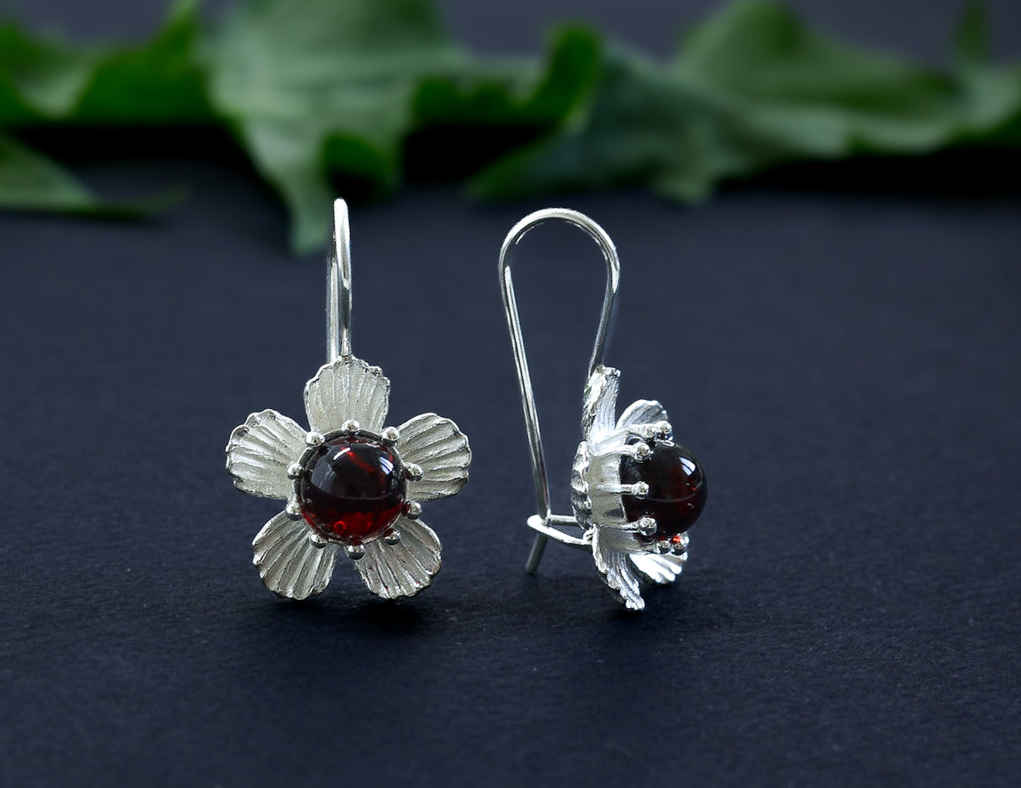 Paar Kirschbernstein Ohrhänger in Blütenform aus 925er Silber (Vorderansicht). Der dunkle Bernstein bildet einen Kontrast zum Silber.