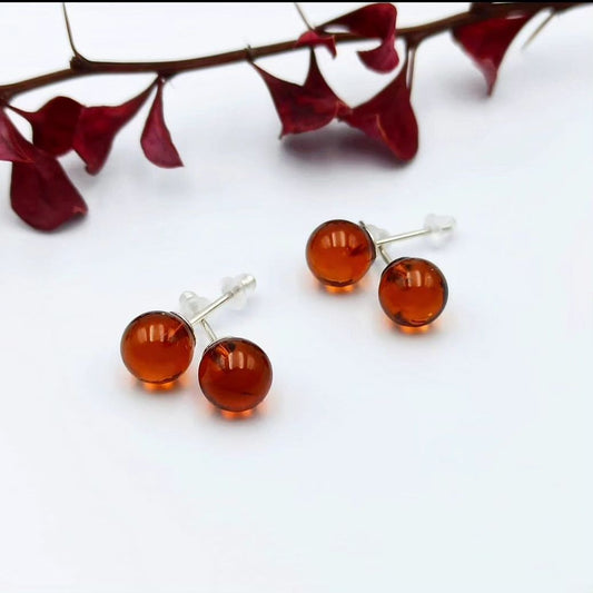 Drei Paare Cognac Baltische Bernstein Kugel-Ohrstecker (⌀7mm, ⌀8mm, ⌀9mm) mit Silberstiften auf weißem Hintergrund.