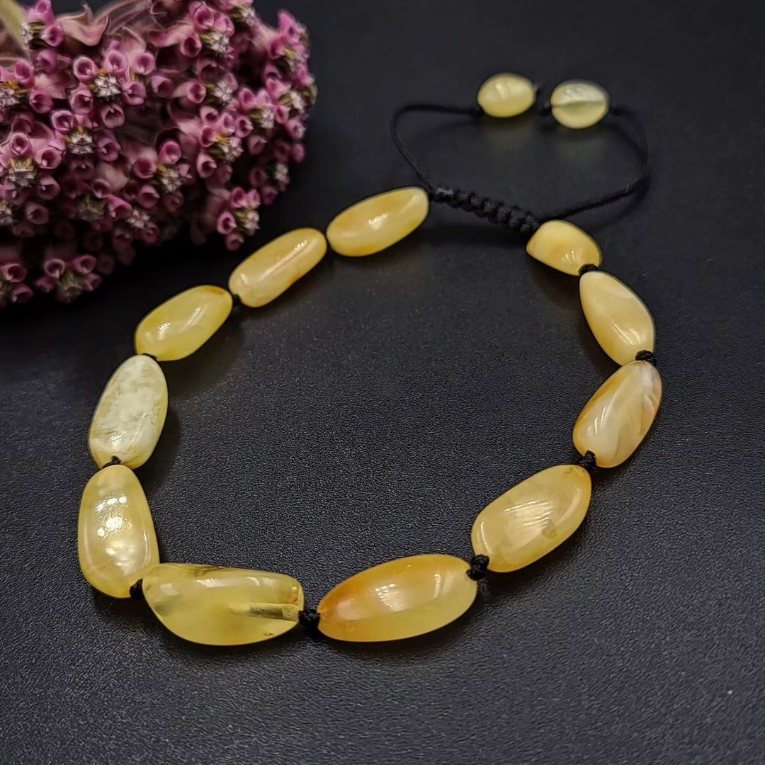 Primäransicht des Tetibel Armbands, hergestellt aus echtem Baltischem Milchbernstein auf schwarzem Makramee-Band.