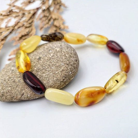 Tetibel Multi-Color Baltic Amber Bracelet featuring polished olive-shaped beads in lemon, honey, and cognac hues on a white background.