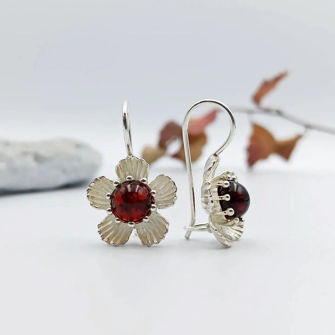 Naturinspirierte Kirschbernstein Ohrhänger von der Seite, Hervorhebung der strukturierten Silberblütenblätter.